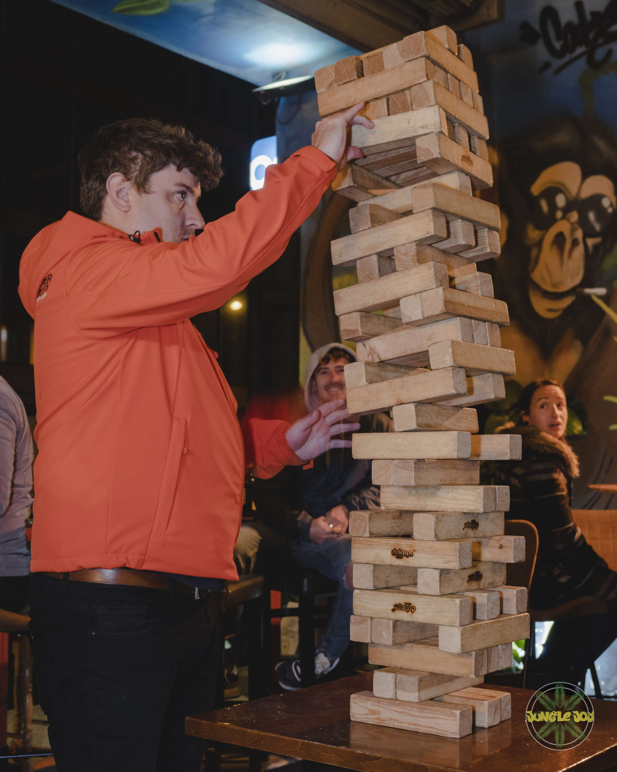Exciting Moment: Player Adds Block to Falling Giant Jenga Tower, Capturing the Thrills of the Game