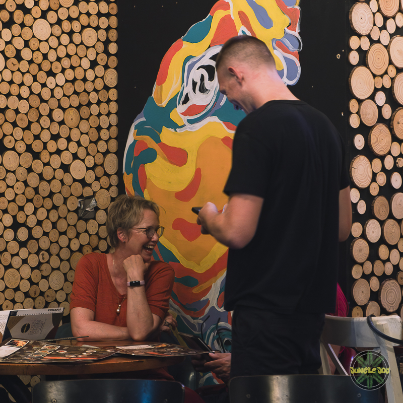 Attentive Jungle Joy Waiter Taking Order from a Happy Customer Against a Vibrant Table Setting